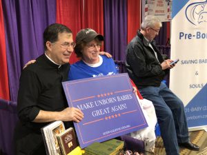 Father Frank Pavone takes a photo with a woman holding a “MAKE UNBORN BABIES GREAT AGAIN” sign. Father Pavone is the National Director of Priests for Life and a staunch pro-life advocate. (Henry Erlandson/MNS)