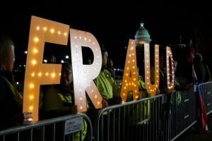 Members of Herndon-Reston Indivisible, a group created to resist President Trump's policies and elect Democrats to office, held lit-up letters spelling “Fraud” and “Yuge Liar.” (Ester Wells/MNS)
