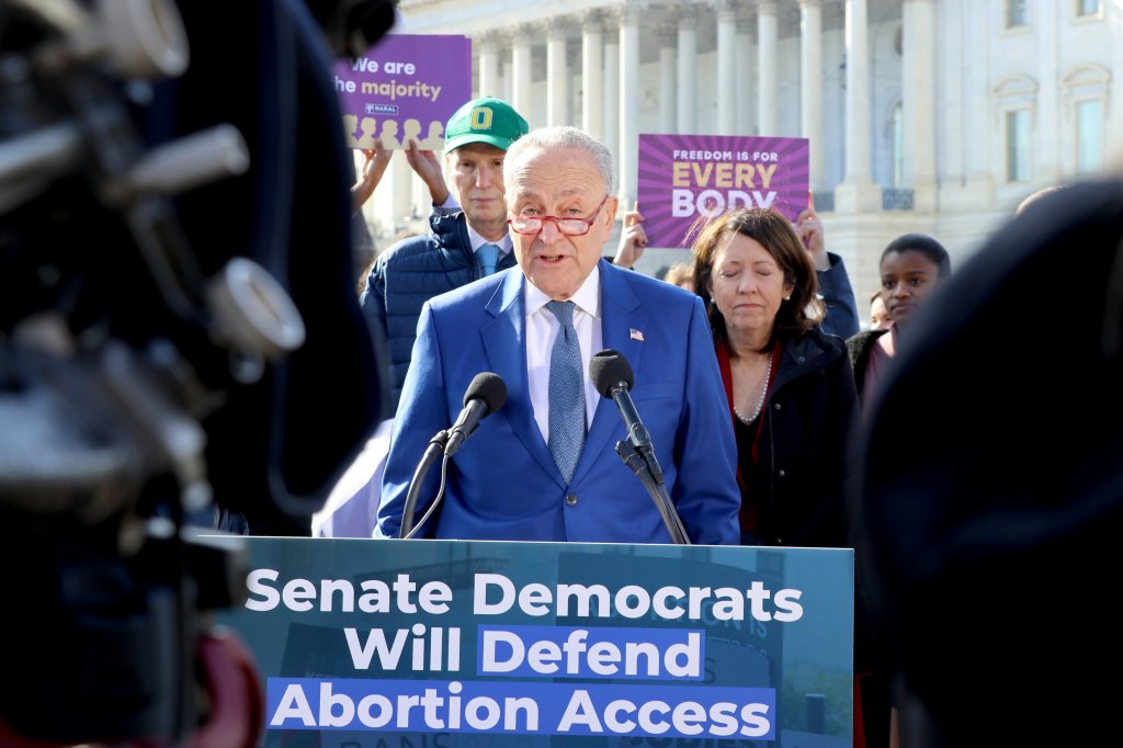 Senate Majority Leader Chuck Schumer speaks at a lectern in front of the Capitol with the phrase "Senate Democrats Will Defend Abortion Access" written on it.