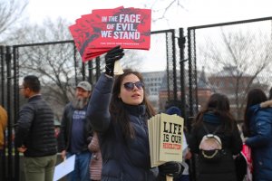 Jasmine Henry, a pro-life activist, handed out signs to marchers before they walked to the Supreme Court. “I wish Trump personally was more supportive, but I’m going to count my wins where I can count them,” she said when asked about the current administration’s abortion policies. (Ben Shapiro/MNS)