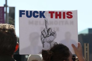 A protester held a sign criticizing Trump for taking away American jobs and causing global humanitarian crises. (Sarah Han/MNS)