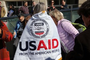 One protester draped USAID flags over her shoulders. (Sarah Han/MNS)